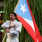 Bad Bunny no palco do Super Bowl com público vibrando e presença de ícones da cultura Hip Hop e latina.